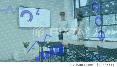 Reviewing two colleagues analyzing charts in meeting room, in blazer and white shirt, near laptop 140876334