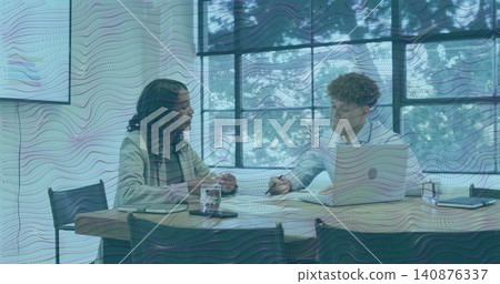 Reviewing papers, woman in cardigan, striped scarf, man in button-down using laptop in meeting room Reviewing papers, woman in cardigan, striped scarf, man in button-down using laptop in meeting room 140876337