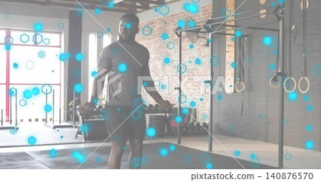 Skipping adult male wearing athletic shirt and shorts in fitness studio, showing jump rope and rig Skipping adult male wearing athletic shirt and shorts in fitness studio, showing jump rope and rig 140876570