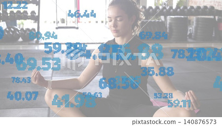 Sitting female meditating on pink mat inside gym with weights big windows black top numeric overlay Sitting female meditating on pink mat inside gym with weights big windows black top numeric overlay 140876573