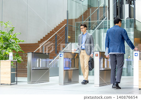 一位商人站在辦公大樓前。 一位商人站在辦公大樓前。 140876654