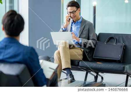 Businessmen waiting while working in the lobby Businessmen waiting while working in the lobby 140876666