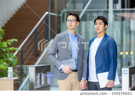 A businessman standing with a smile in front of an office building. A businessman standing with a smile in front of an office building. 140876683