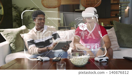 Holding tablet, two men cream-sweater and red-shirt using VR-headset on sofa at home, AR overlay Holding tablet, two men cream-sweater and red-shirt using VR-headset on sofa at home, AR overlay 140876812