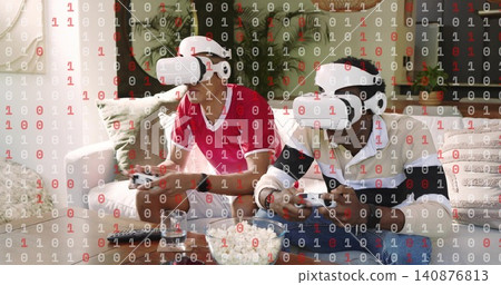 Playing two adults wearing white VR headsets and holding controllers at home on sofa with popcorn Playing two adults wearing white VR headsets and holding controllers at home on sofa with popcorn 140876813