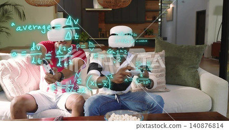 Playing two adults wearing red and striped tops, VR headsets, holding gamepads on sofa with popcorn 140876814