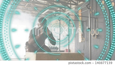 Jumping athlete in dark shorts, short-sleeve top on plyometric box at studio, with rings, teal HUD Jumping athlete in dark shorts, short-sleeve top on plyometric box at studio, with rings, teal HUD 140877139