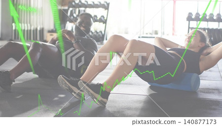 Rolling woman in black sportswear on gym floor, reclining man in dark clothes, blue foam roller Rolling woman in black sportswear on gym floor, reclining man in dark clothes, blue foam roller 140877173