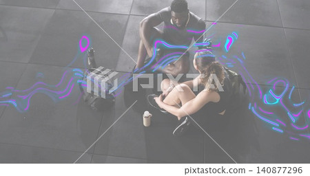 Sitting partners wearing sportswear adjusting shoes on gym tiles with backpacks shaker neon swirl Sitting partners wearing sportswear adjusting shoes on gym tiles with backpacks shaker neon swirl 140877296