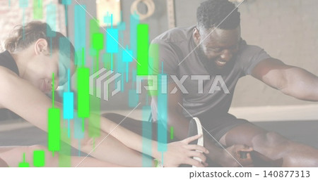 Stretching two training partners in athletic wear reaching feet in gym on mats, candlestick overlay Stretching two training partners in athletic wear reaching feet in gym on mats, candlestick overlay 140877313