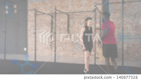 Coaching female trainer guiding male trainee in gym studio, with pull-up rig and athletic clothing 140877328