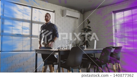 Standing man wearing dark shirt, leaning hand on chair at meeting table, with laptop carafe Standing man wearing dark shirt, leaning hand on chair at meeting table, with laptop carafe 140877362