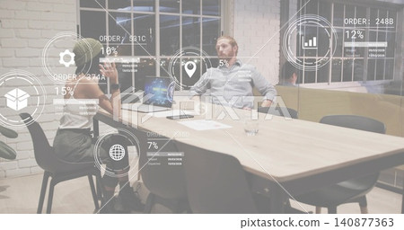 Discussing two coworkers in biz-casual reviewing laptop, papers on office table, and AR overlays 140877363