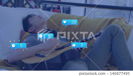 Reclining teenage male napping on couch at window holding guitar headset and reactions, copy space 140877495