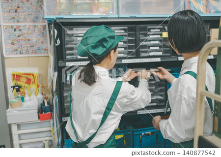 Two staff members organizing the storage shelves in the back room. Two staff members organizing the storage shelves in the back room. 140877542