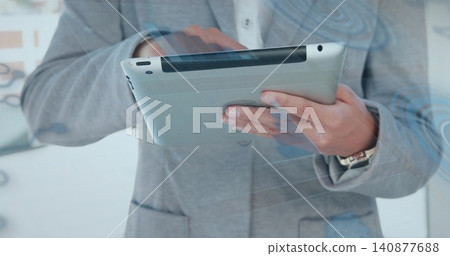 Holding tablet, professional in gray blazer in office, showing wristwatch with blue glass overlays Holding tablet, professional in gray blazer in office, showing wristwatch with blue glass overlays 140877688