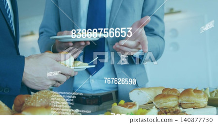 Gesturing with tablet, two men in suits holding plates at office buffet with data overlays Gesturing with tablet, two men in suits holding plates at office buffet with data overlays 140877730