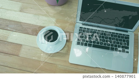Showing silver laptop with open lid on wooden tabletop, with ceramic cup, pink planter, map overlay Showing silver laptop with open lid on wooden tabletop, with ceramic cup, pink planter, map overlay 140877901