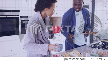 Preparing couple in robes chopping bread and holding mugs at kitchen island, showing map overlay Preparing couple in robes chopping bread and holding mugs at kitchen island, showing map overlay 140877917
