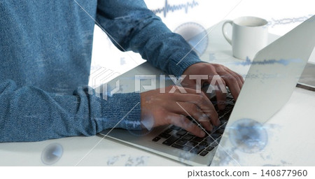 Typing man wearing blue knit sweater on silver laptop at home office desk, with coffee mug Typing man wearing blue knit sweater on silver laptop at home office desk, with coffee mug 140877960