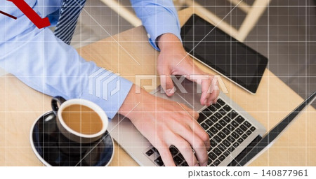 Typing man wearing blue shirt and striped tie at wood desk, laptop, red arrow, grid overlay 140877961