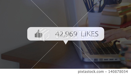 Typing hands with rings on open laptop at wooden desk, pop-up showing 42,969 LIKES, copy space Typing hands with rings on open laptop at wooden desk, pop-up showing 42,969 LIKES, copy space 140878034