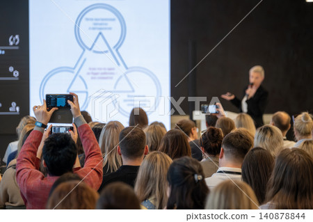 Audience recording keynote presentation at business conference, people using smartphones to capture slide Audience recording keynote presentation at business conference, people using smartphones to capture slide 140878844
