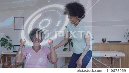 Older woman in pink shirt performing arm curls in therapy, therapist supporting pink weights and AR Older woman in pink shirt performing arm curls in therapy, therapist supporting pink weights and AR 140878969