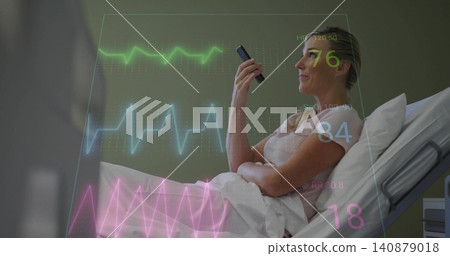 Reclining patient in hospital bed in short-sleeve top, holding device and looking upward with ECG Reclining patient in hospital bed in short-sleeve top, holding device and looking upward with ECG 140879018