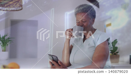 Sipping senior woman holding gray mug and checking smartphone at modern kitchen counter, copy space Sipping senior woman holding gray mug and checking smartphone at modern kitchen counter, copy space 140879020
