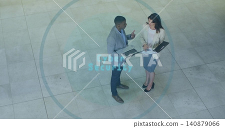 Discussing colleagues in blazers holding laptop and folder at corporate atrium, Cyber Security text Discussing colleagues in blazers holding laptop and folder at corporate atrium, Cyber Security text 140879066