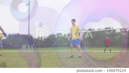 Holding position central player in yellow jersey and blue shorts on grassy pitch, goal net Holding position central player in yellow jersey and blue shorts on grassy pitch, goal net 140879124