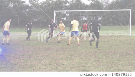 Contesting men in yellow shirts and black kits jumping at grassy goal, with soccer ball airborne Contesting men in yellow shirts and black kits jumping at grassy goal, with soccer ball airborne 140879153
