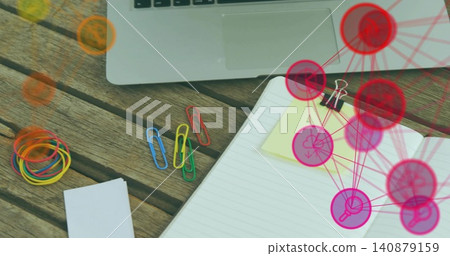 Showing open notebook with yellow note clipped by clip sitting at desk, laptop and pink or red overl Showing open notebook with yellow note clipped by clip sitting at desk, laptop and pink or red overl 140879159