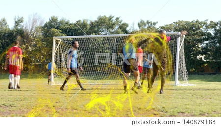 Players in red or yellow kits and blue bibs defending goal on pitch, with gloved keeper, yellow pain Players in red or yellow kits and blue bibs defending goal on pitch, with gloved keeper, yellow pain 140879183