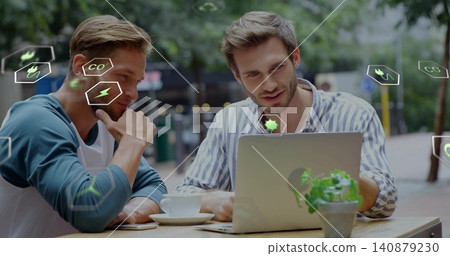 Collaborating on laptop pair in striped shirt, blue raglan, cafe with coffee cup, plant, eco icons 140879230
