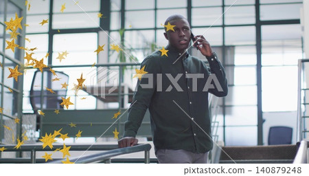 Speaking man wearing green shirt holding smartphone to ear at office atrium, gold stars, copy space 140879248
