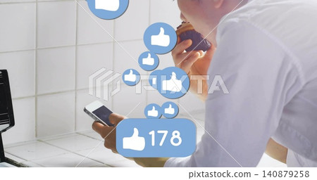 Leaning Asian man white shirt holding phone eating cupcake kitchen counter 178 likes, copy space Leaning Asian man white shirt holding phone eating cupcake kitchen counter 178 likes, copy space 140879258