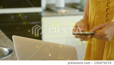 Using phone senior-male in yellow top tapping laptop on counter, yellow particles, copy space Using phone senior-male in yellow top tapping laptop on counter, yellow particles, copy space 140879259