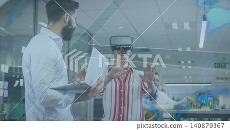Reaching woman in striped shirt using VR headset interacting with virtual UI at office, with laptop Reaching woman in striped shirt using VR headset interacting with virtual UI at office, with laptop 140879367