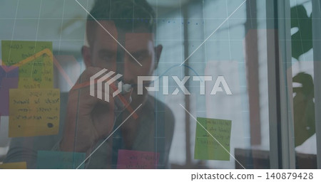 Drawing man in gray shirt annotating glass panel at office, holding marker, sticky notes, red arrow Drawing man in gray shirt annotating glass panel at office, holding marker, sticky notes, red arrow 140879428