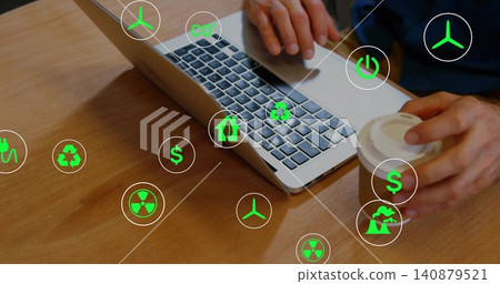 Typing dark-sleeved hands using silver laptop keys at desk, holding paper cup amid green icons 140879521