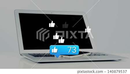 Displaying laptop and phone on glossy white table, showing like icons and blue 73 bubble Displaying laptop and phone on glossy white table, showing like icons and blue 73 bubble 140879537