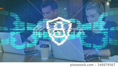 Typing two male coworkers in casual clothes at wooden table using laptops, papers, security overlay Typing two male coworkers in casual clothes at wooden table using laptops, papers, security overlay 140879567