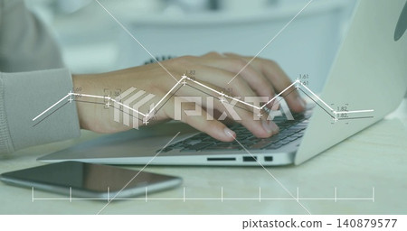 Typing male's hands wearing light gray cuff on laptop at home desk, with smartphone, chart overlay Typing male's hands wearing light gray cuff on laptop at home desk, with smartphone, chart overlay 140879577