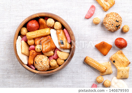 Japan mix, Japanese rice crackers and coated peanuts in wooden bowl on linen. Crackers made from baked rice and wheat flour, brushed with soy sauce, sprinkled with seaweed and sesame seeds. Photo Japan mix, Japanese rice crackers and coated peanuts in wooden bowl on linen. Crackers made from baked rice and wheat flour, brushed with soy sauce, sprinkled with seaweed and sesame seeds. Photo 140879593