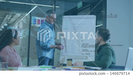 Presenting presenter in light blue shirt gesturing at flip chart in glass meeting room, with laptop Presenting presenter in light blue shirt gesturing at flip chart in glass meeting room, with laptop 140879714