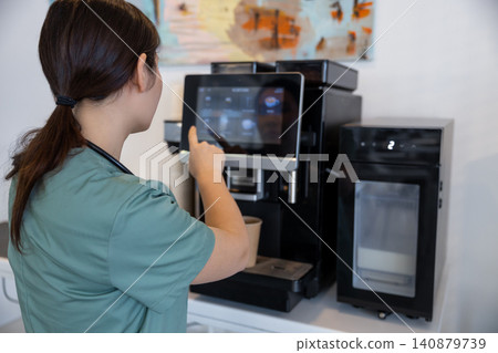Tired female doctor making herself coffee in a hospital kitchen 140879739