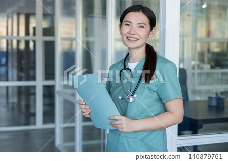 Asian young female doctor smiling nicely and feeling positive Asian young female doctor smiling nicely and feeling positive 140879761