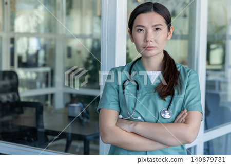 Cute young female doctor in lab coat and with stethoscope around her neck Cute young female doctor in lab coat and with stethoscope around her neck 140879781